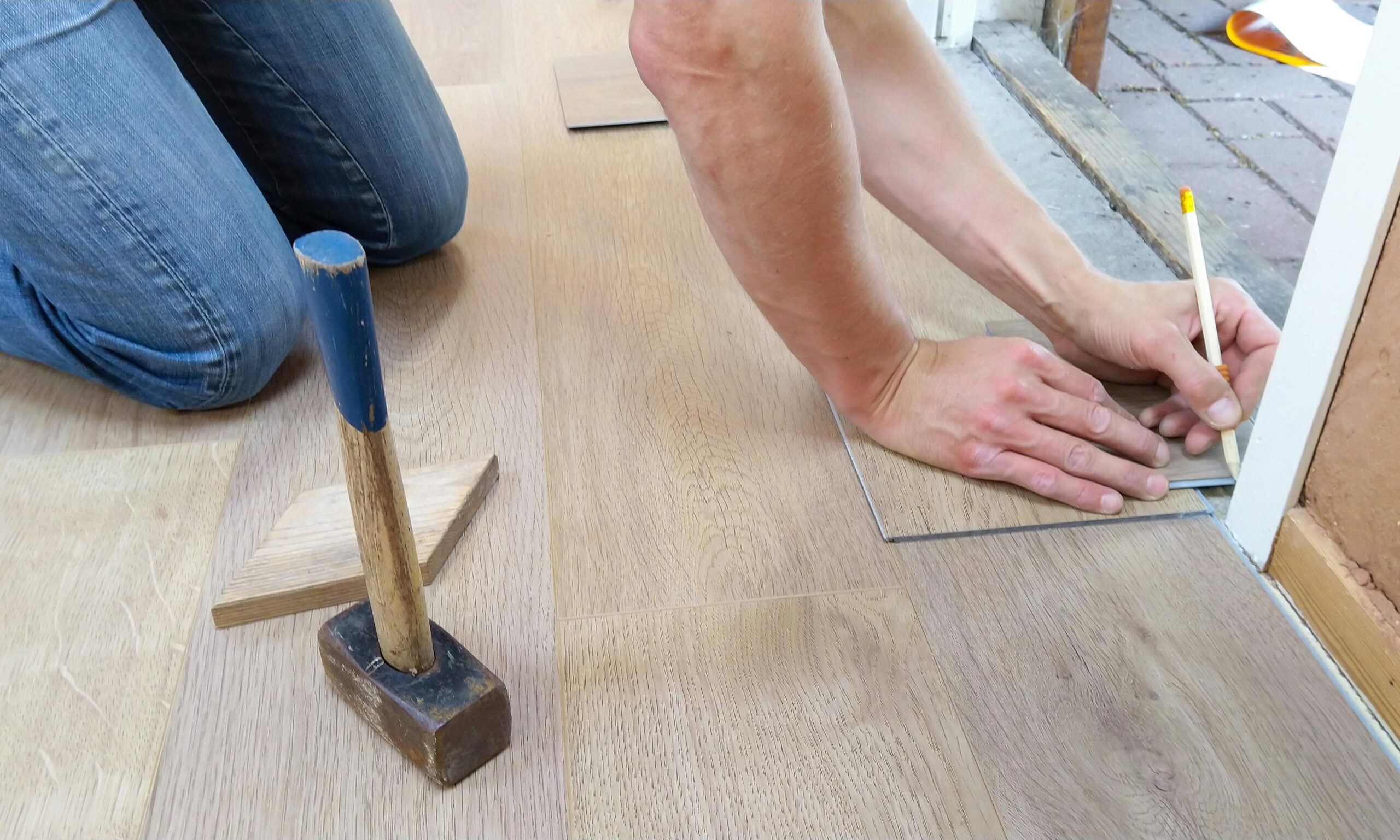 Worker installing hardwood flooring with precision tools